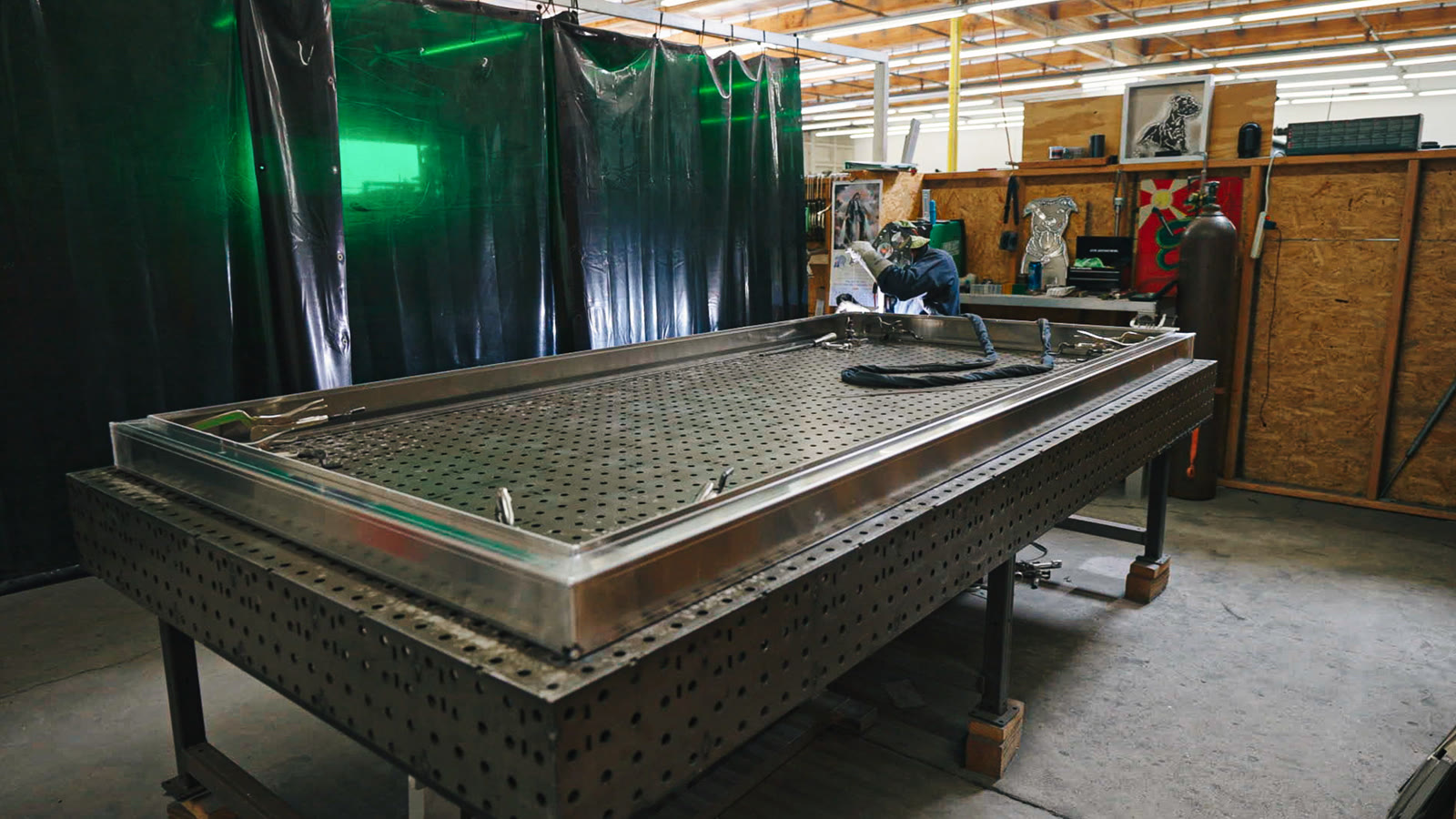 Wide view of a large silver rectangular frame laid across the perforated fabrication table.