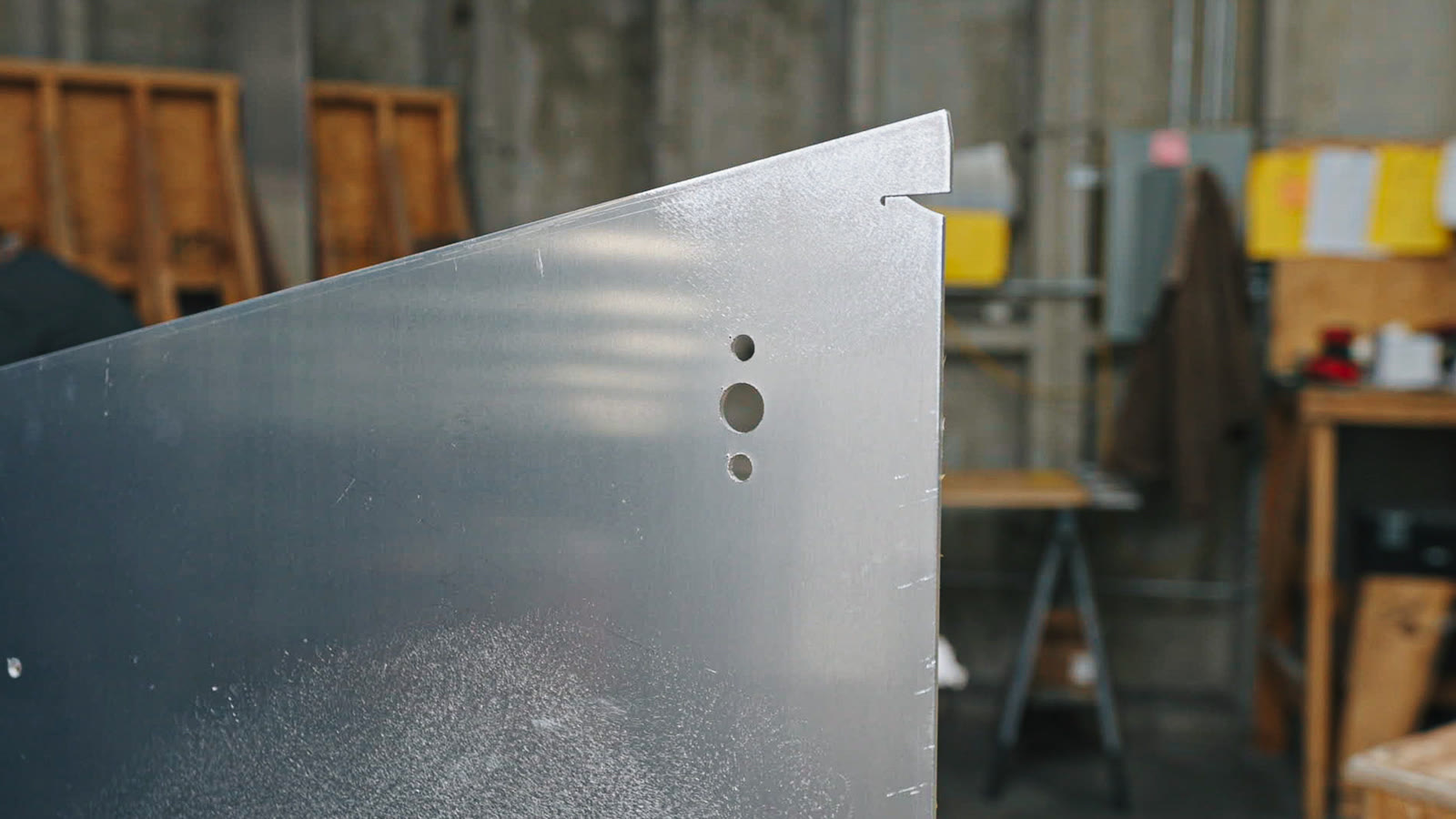Close view of the corner and folded edge of a silver panel with several small round holes.