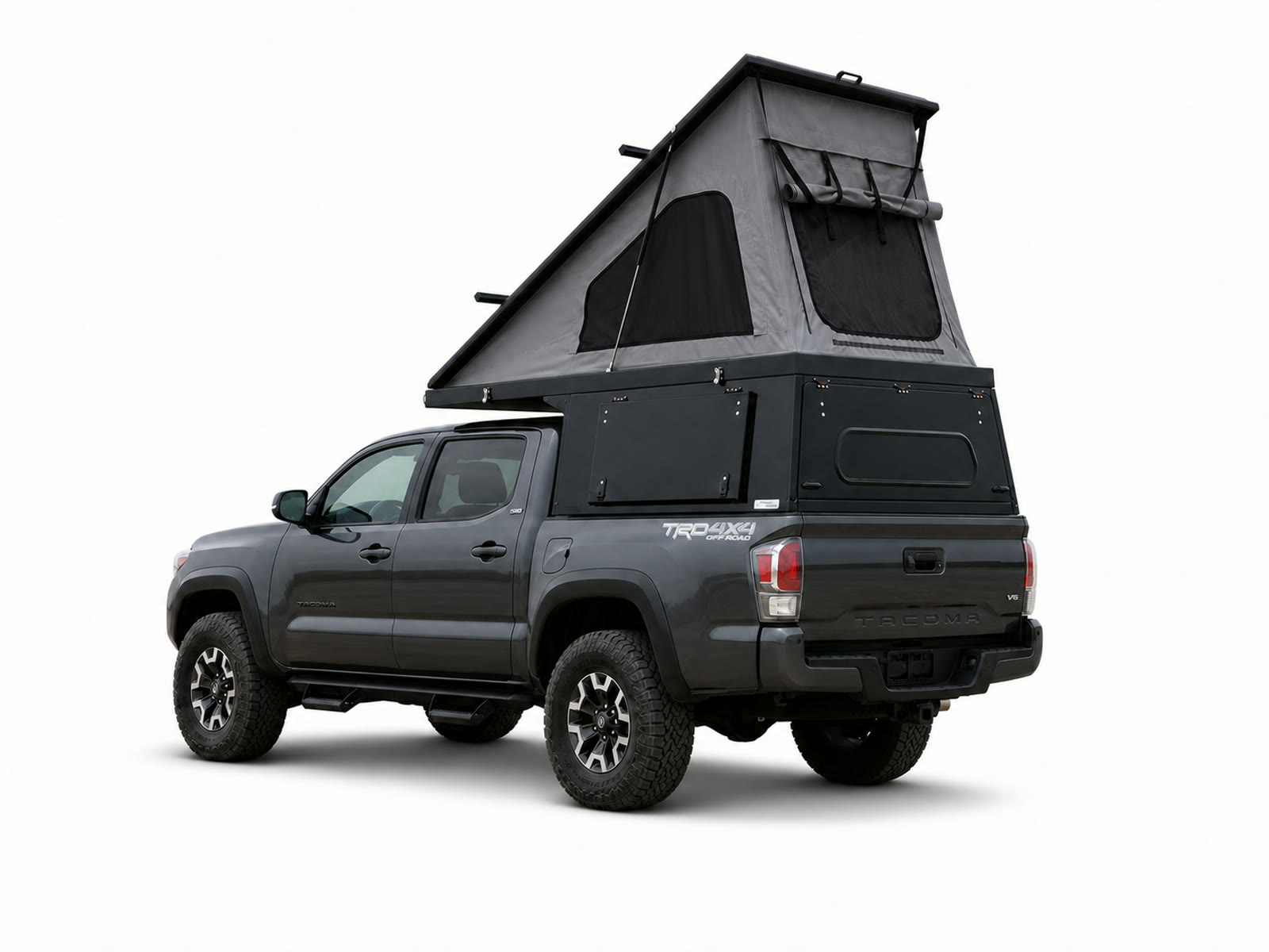 Rear three-quarter view of a gray Toyota Tacoma carrying an open black Topo Toppers Mesa wedge camper on a white background.