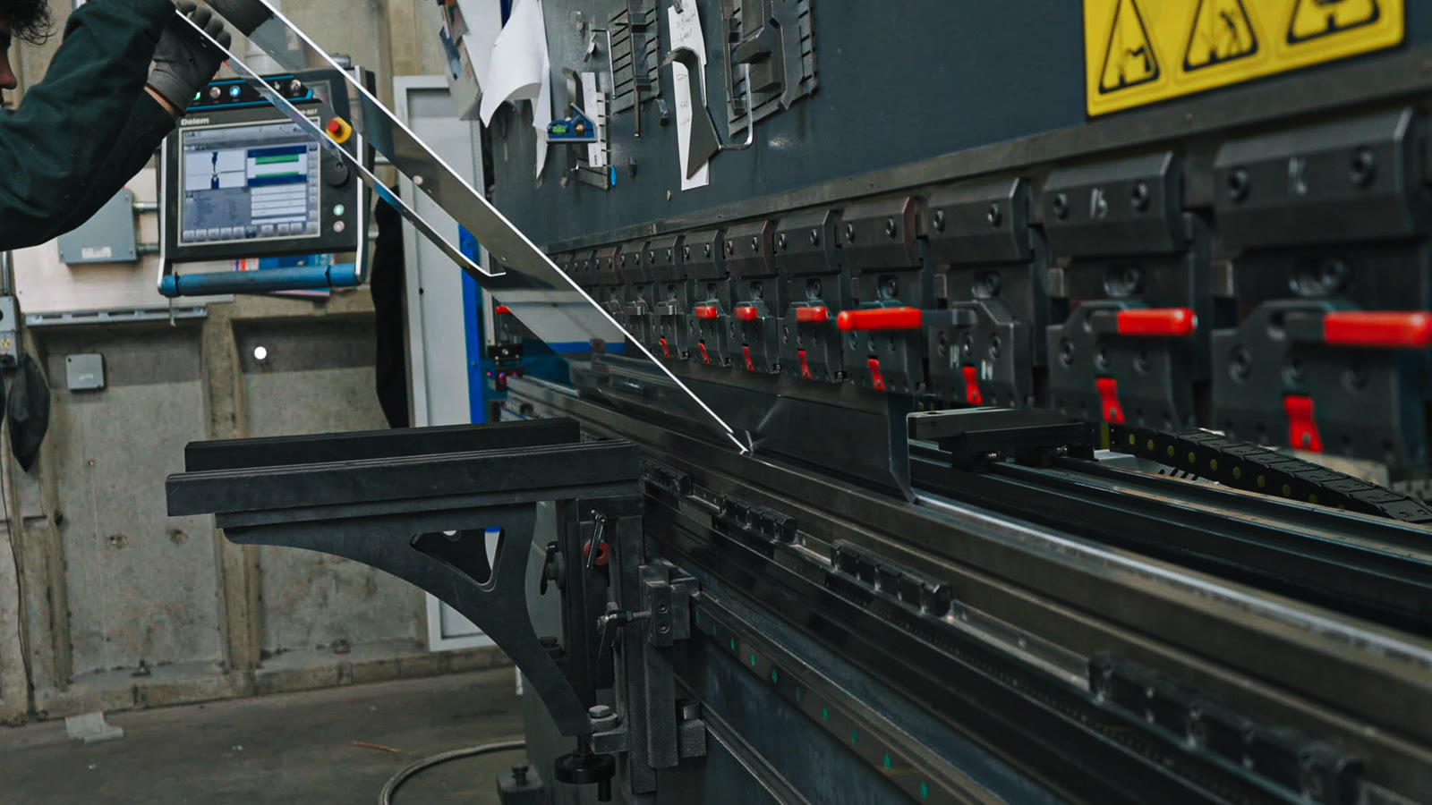 Close side view of the bending machine with a long angular metal piece extending from its tooling.