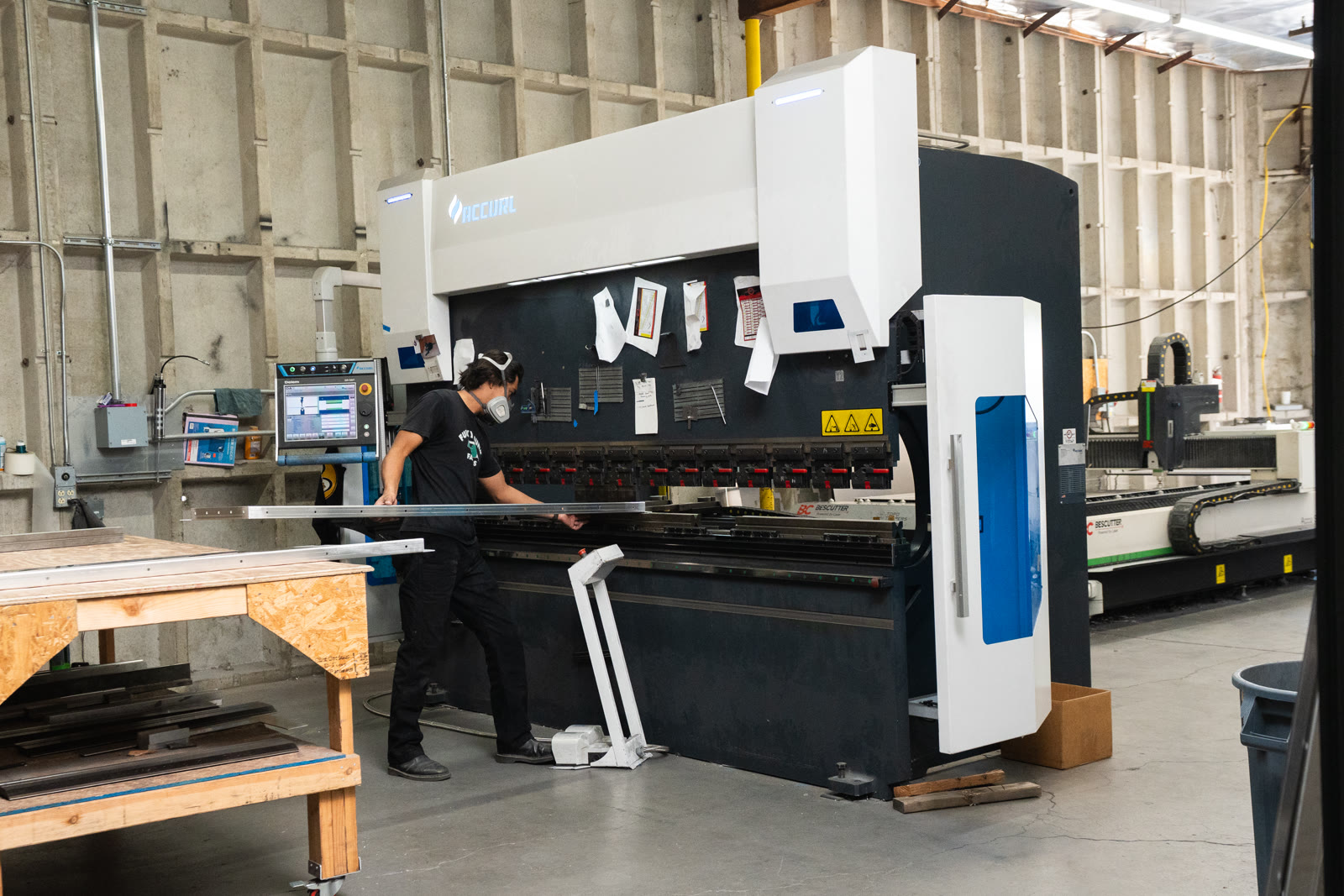 A worker stands at the center of the large white-and-black press brake inside the factory.