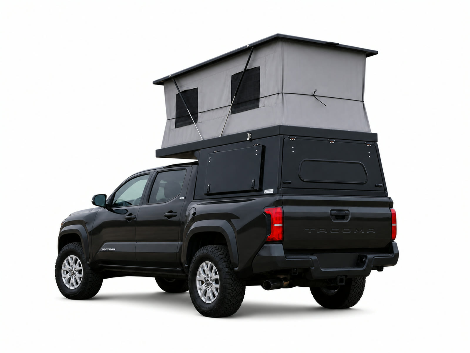 Rear three-quarter view of a black Toyota Tacoma carrying an open black Topo Toppers Badlander camper with a tall gray pop-up on a white background.